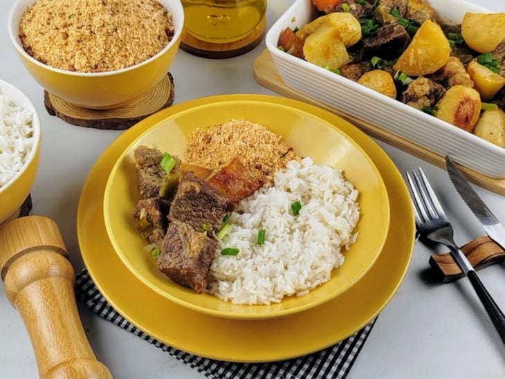 carne de panela com batatas finalizada e servida com arroz e farofa.