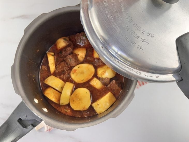 Uma panela de pressão contendo carne e batata.