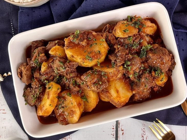 Uma travessa contendo carne de panela com batatas.