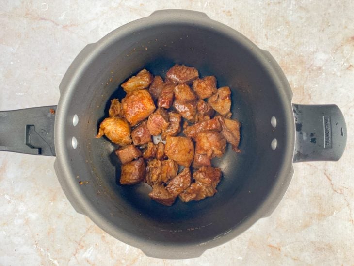 Uma panela de pressão com a carne a cozinhar.