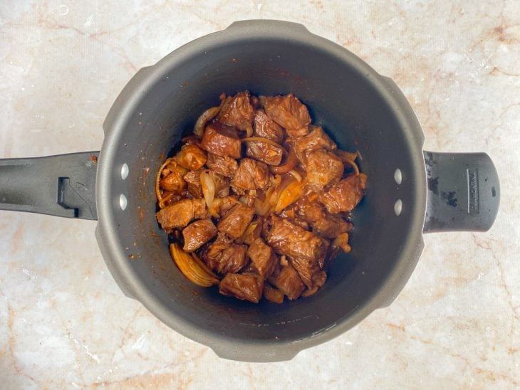 Uma panela com a carne, molho inglês, extrato de tomate e temperos.