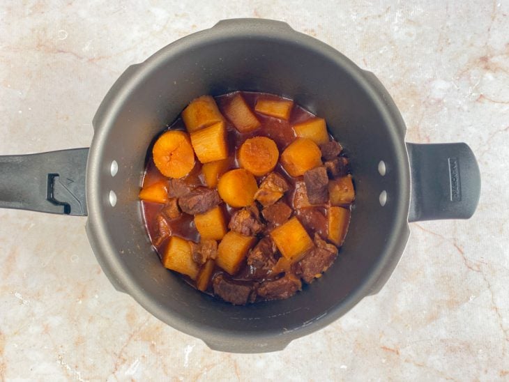 Panela de pressão com a carne, o molho e a mandioca ao ponto.