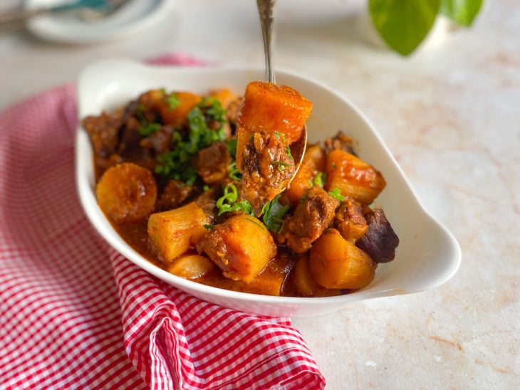 Um refratário contendo carne de panela com mandioca.