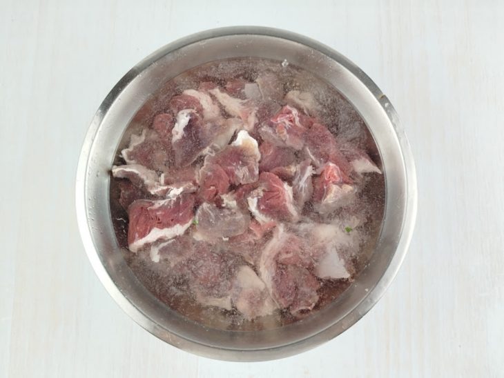 Carne dessalgando num recipiente redondo de inox.