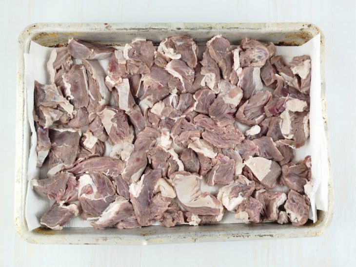 Carne colocada sobre um pano limpo numa assadeira.