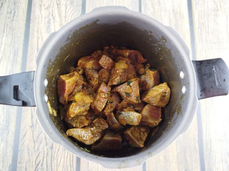 Carne cozinhando na panela de pressão com caldo.