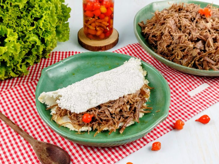 Prato finalizado com carne desfiada e acompanhamentos.