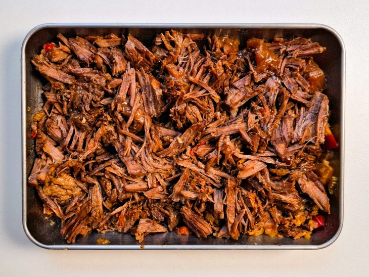 Carne desfiada num recipiente retangular.