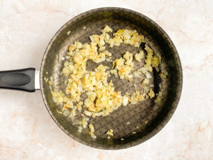 Cebola refogada numa frigideira.