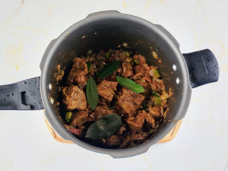 Folhas de loura, pimentão e tomate adicionados a panela.