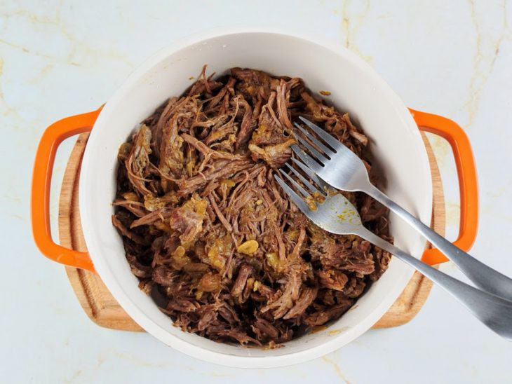 Carne sendo desfiada com um garfo.