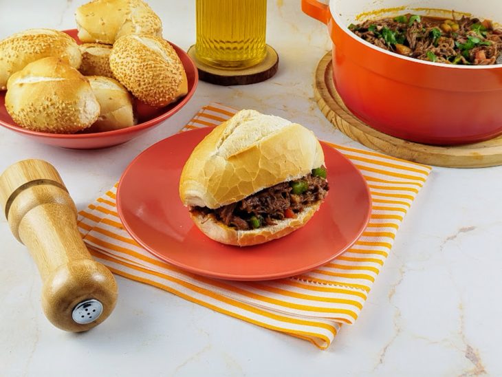 Pão francês recheado com a carne louca sobre um prato.