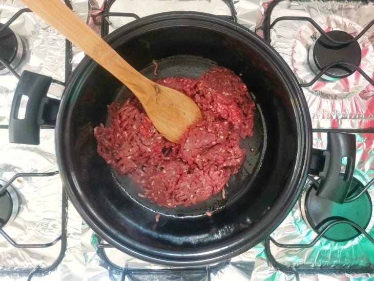 Panela com carne moída ainda crua e grudada.