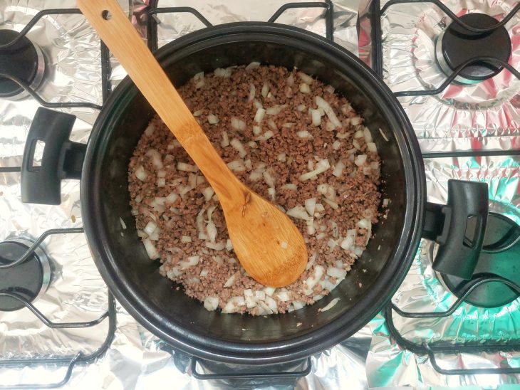 Cebola e alho incorporados na carne moída na panela.