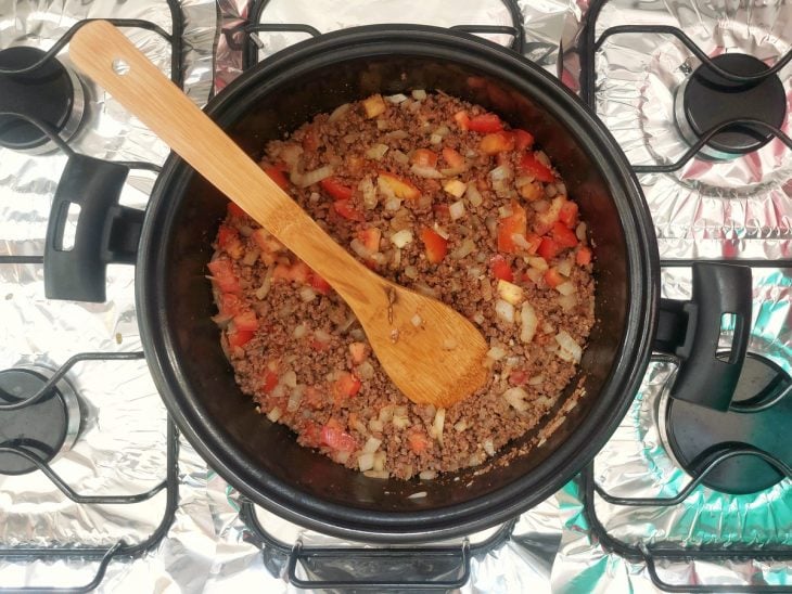 Tomates picados adicionados na carne moída na panela.