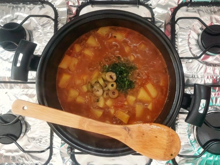 Carne moída sendo finalizada com azeitonas e cheiro-verde na panela ainda.