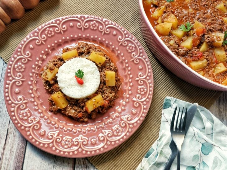 Carne moída om batatas servida com arroz em um prato.