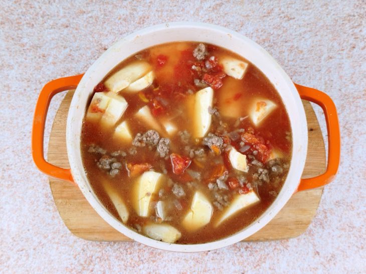 Mandioca, molho de tomate e água adicionados na panela.