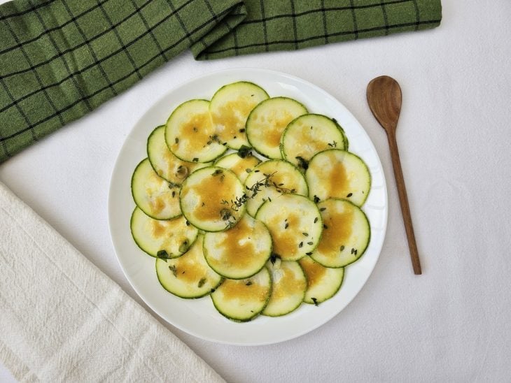 Um prato contendo carpaccio de abobrinha com molho de mostarda.