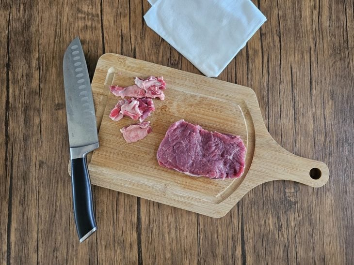 Tábua carne para carpaccio com alguns pedaços de gordura ao lado.