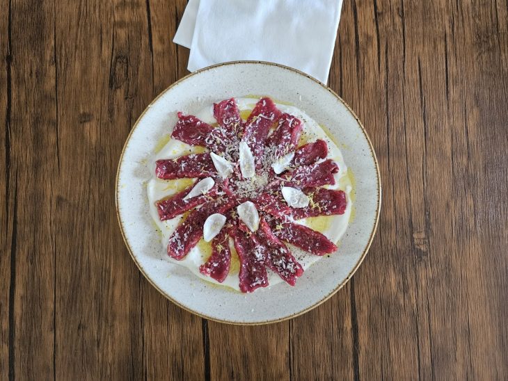 Picles e temperos adicionados por cima do carpaccio de carne e coalhada.