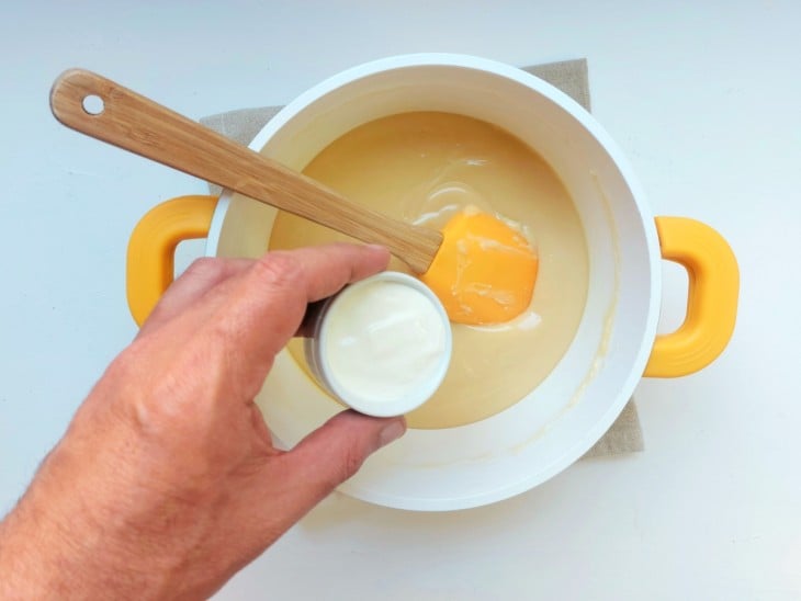 Creme de leite sendo adicionado na panela com brigadeiro branco.