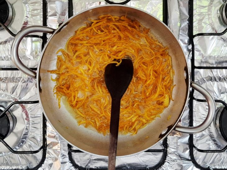 açúcar derretendo em caramelo na cristalização das cascas de laranja.