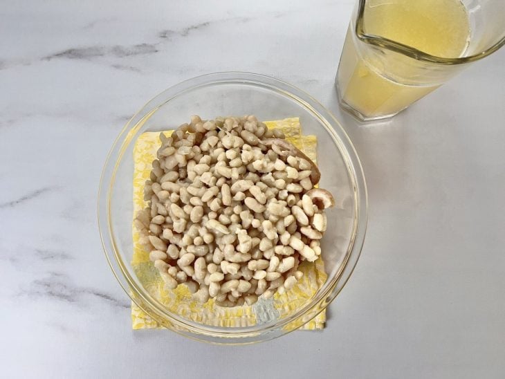 Uma tigela com o feijão coado e o caldo separado.