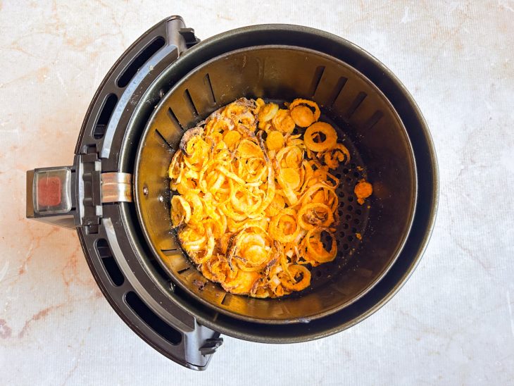 Cebola no cesto da airfryer, após parte do tempo.