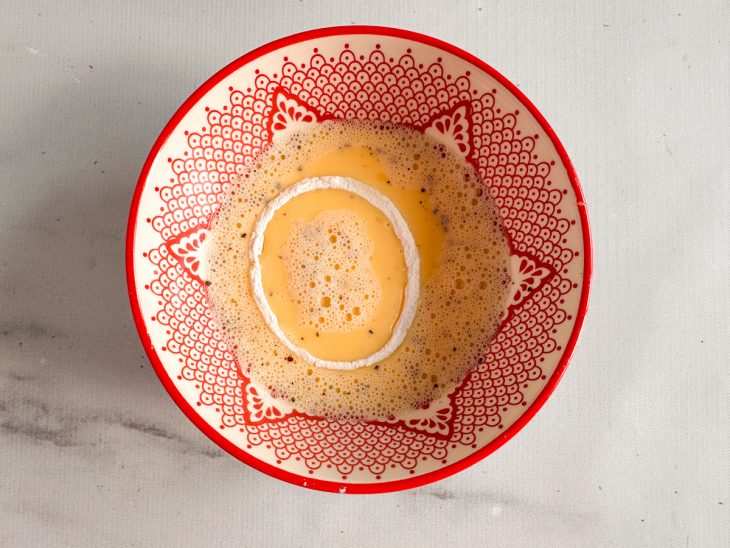 Anéis de cebola na mistura de ovos e leite.