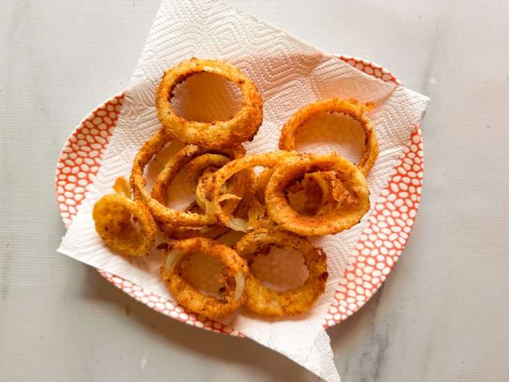 Anéis de cebola escorrendo no papel toalha.