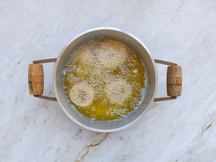 Anéis de cebola sendo fritos no óleo.