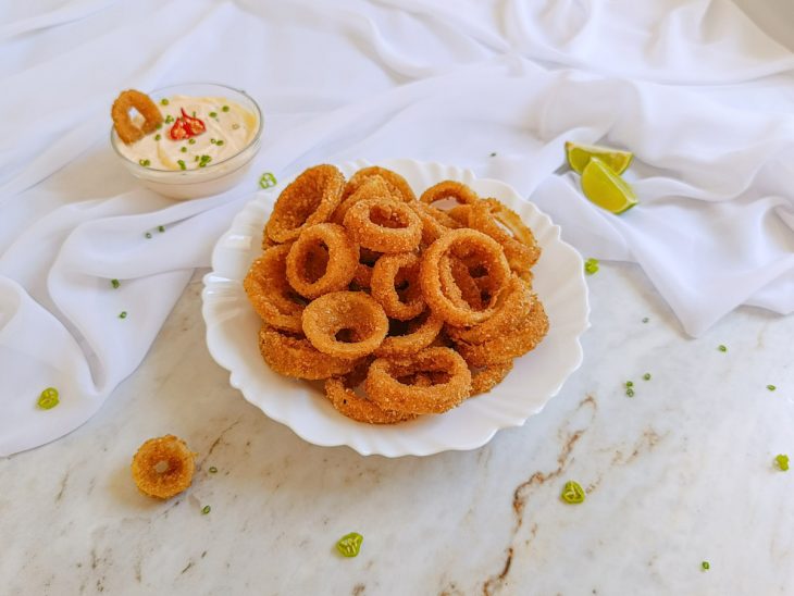 Anéis de cebola prontos, servidos em prato.