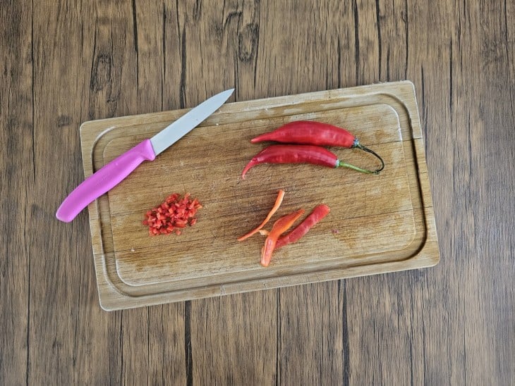 Pimenta-dedo-de-moça cortada em tiras e pedacinhos menores em uma tábua.