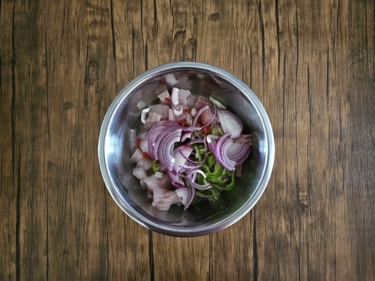 Temperos cortados com o peixe em cubinhos em uma tigela.