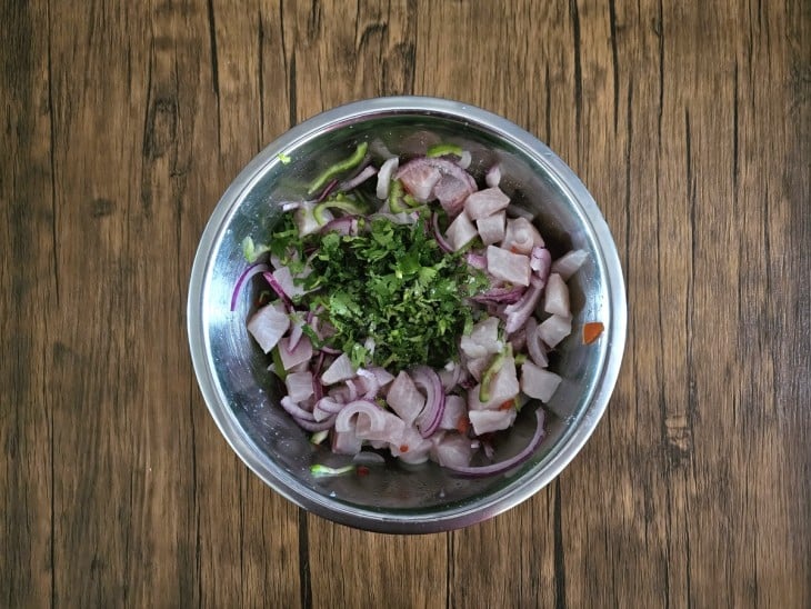 Coentro e sal adicionados na mistura de peixe e temperos.