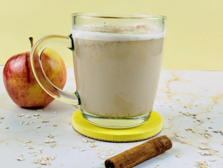 Chá de leite de aveia e maçã pronto para consumo em uma xícara de vidro.
