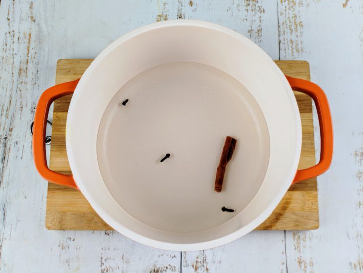 Uma panela com água, cravo e canela.