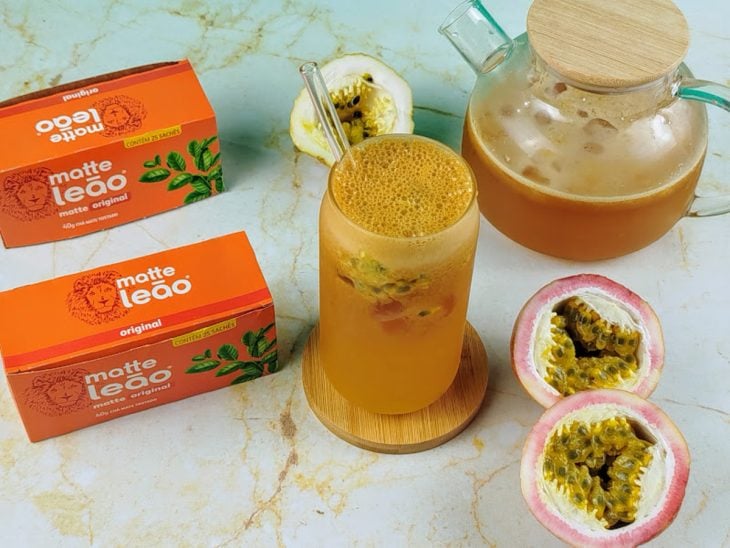 Chá-mate com maracujá pronto para consumo em um copo de vidro.