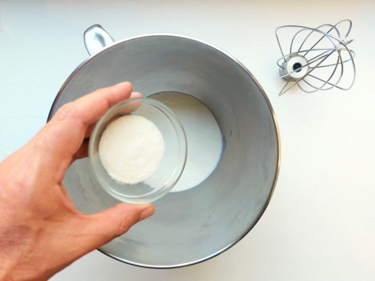 Açúcar sendo adicionado na batedeira com creme de leite.