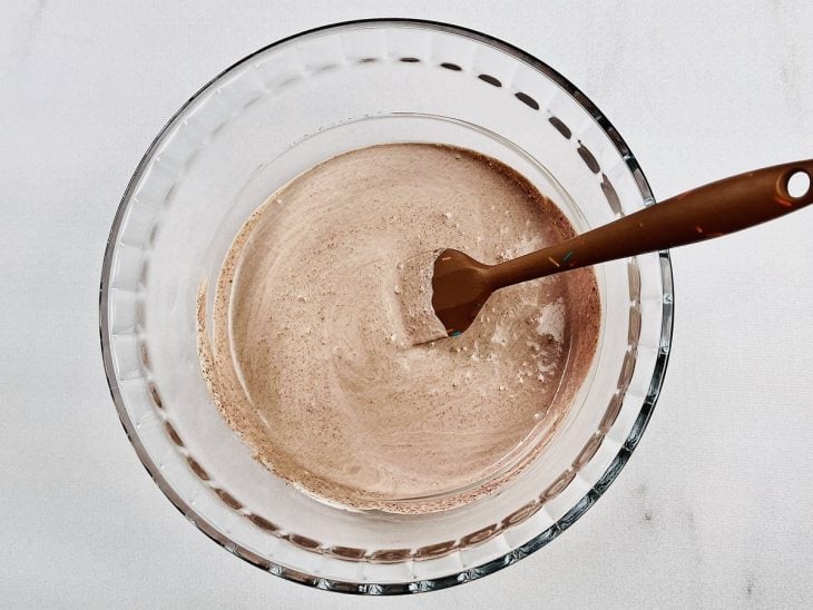 Mistura para chantilly e chocolate em pó misturados em na tigela de vidro.