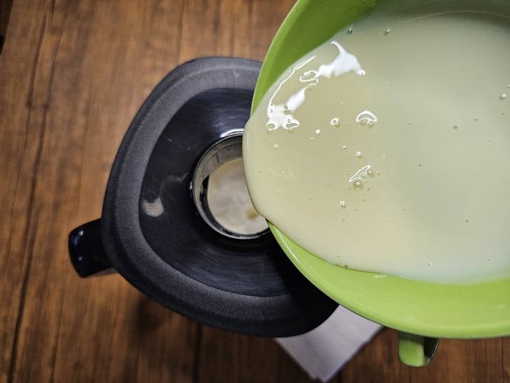 Um liquidificador contendo creme de leite e leite condensado sendo batido.