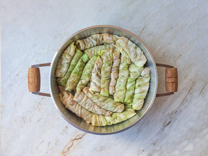 Charutos de repolho dispostos lado a lado em camadas dentro da panela.