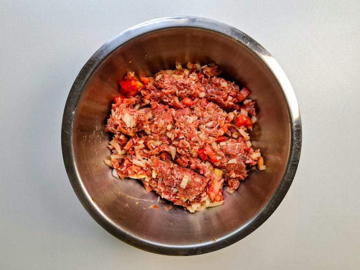 Carne, arroz e temperos misturados na tigela.