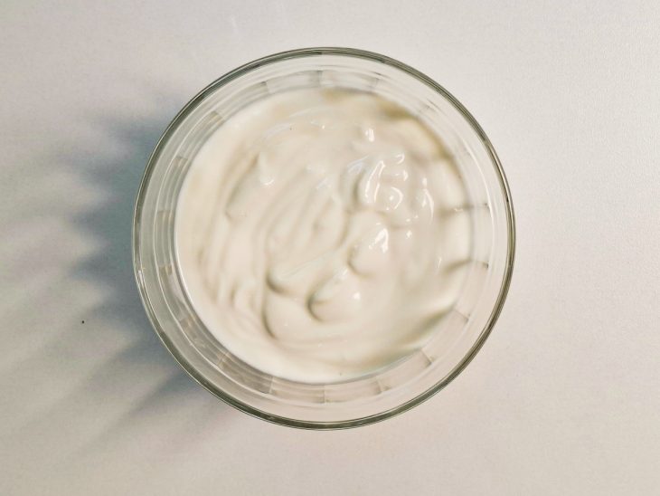 Iogurte natural transferido para um recipiente de vidro individual.