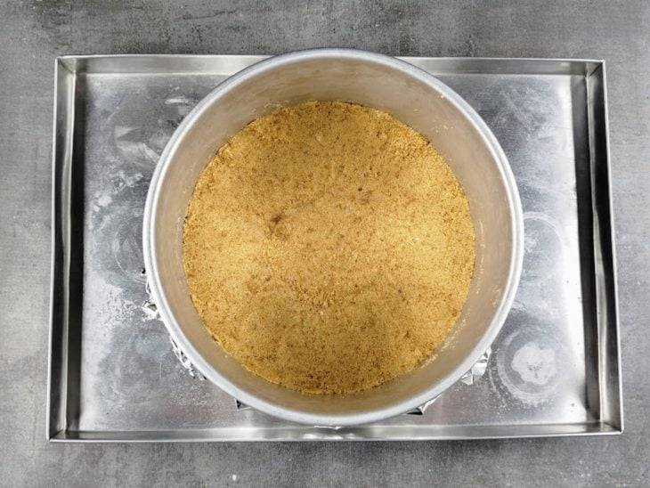 Uma forma com a base do cheesecake em uma assadeira.