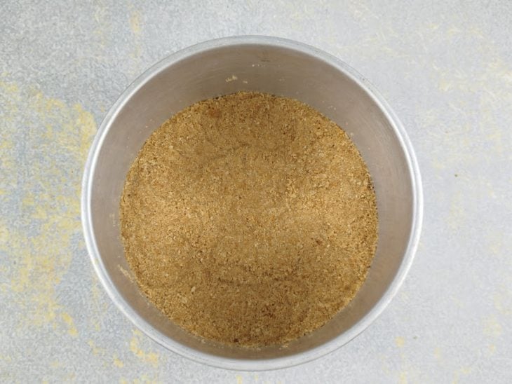 Farofa de biscoito e manteiga moldada no fundo da forma.