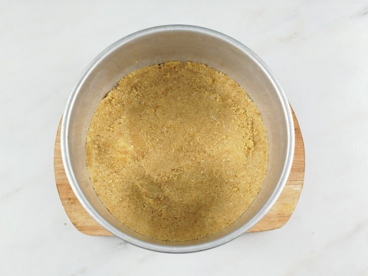 Farofa de bolacha acomodada no fundo da forma.
