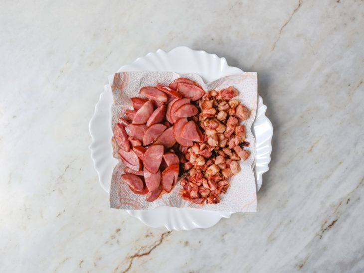 Bacon e calabresa dourando na frigideira.