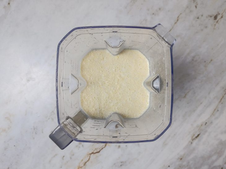 Milho sendo batido no liquidificador com creme de leite e água.